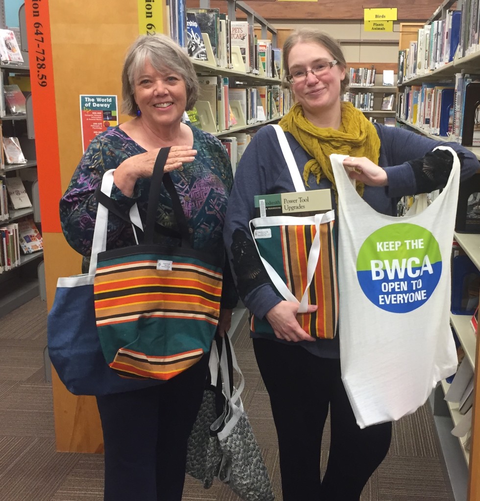 Nancy Backlund, incoming president of the Northwoods Fiber Guild and Amanda St. John, assistant director of the library, show to cloth book bags now available for use at the library. They are free for everyone to use.