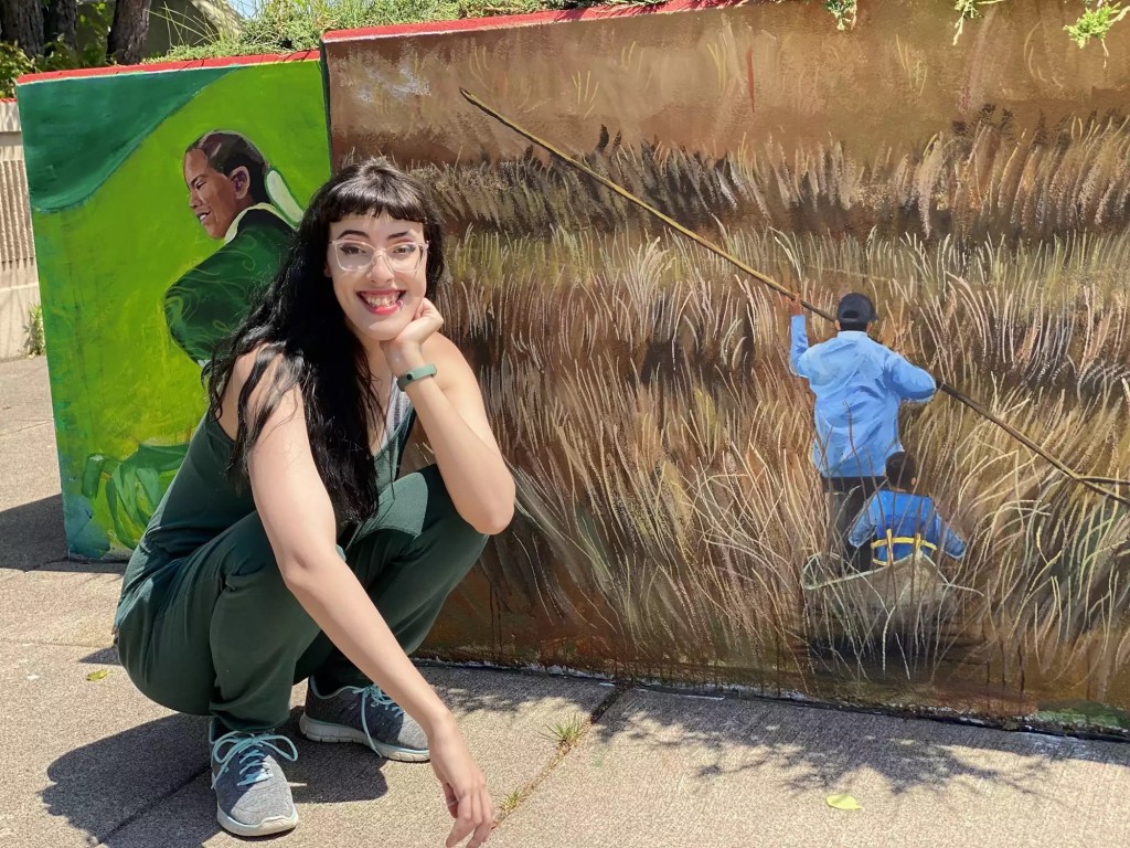 Moira Villiard, coordinator of the Chief Buffalo Memorial Mural project in Duluth, crouches in front of a wall she painted of a man harvesting wild rice. July 13. Photo by Dan Kraker | MPR News. To read the story, click here.