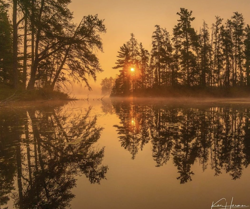 Sunrise on a foggy lake by Ken Harmon.